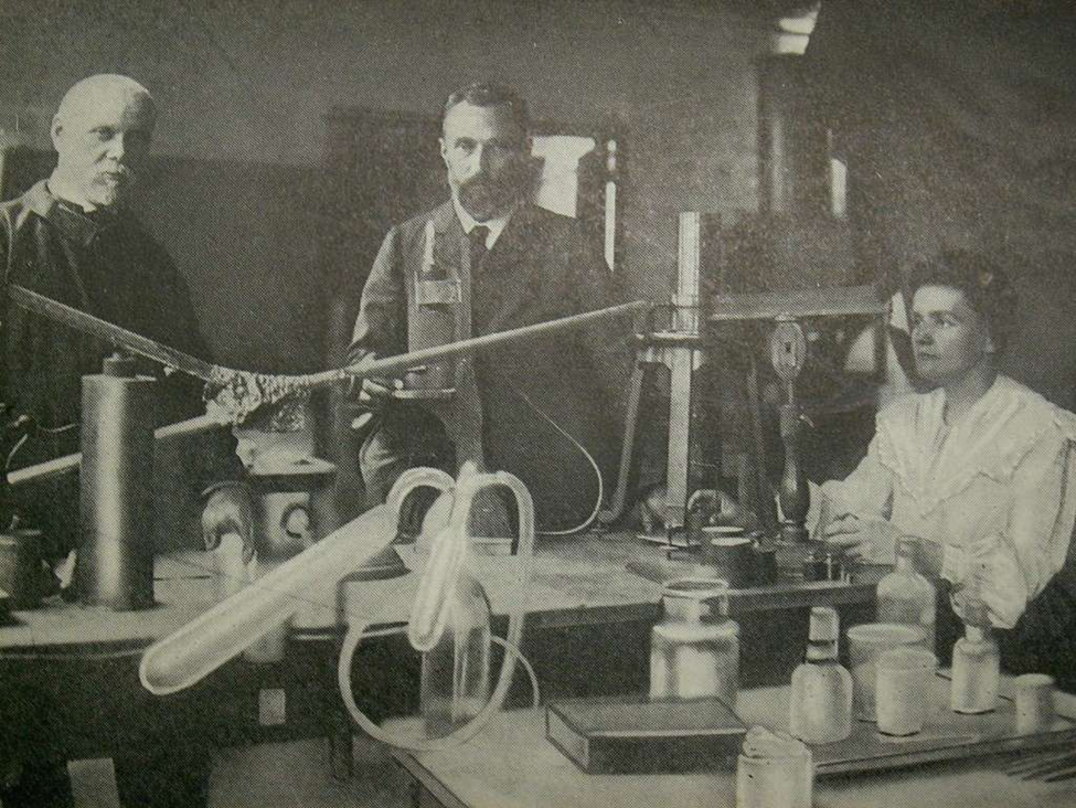 Three people in a black and white photograph behind a scientific laboratory bench setting